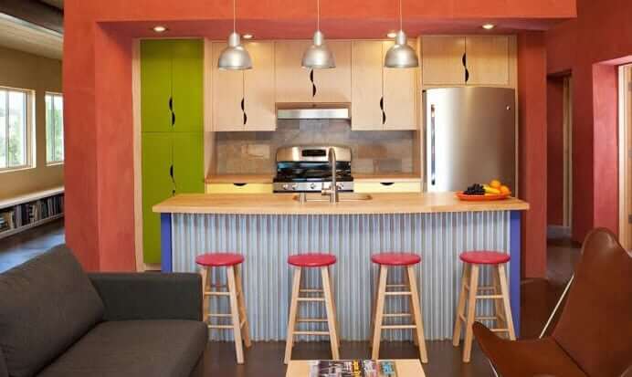 A kitchen with vibrant walls and stools, designed by a Santa Fe home designer.