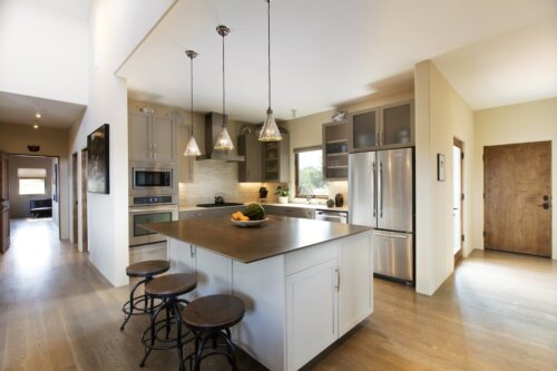 A modern kitchen with a center island and stools designed by a Santa Fe architect.