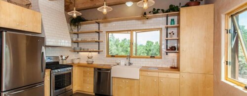 A Santa Fe kitchen in a tiny house with wooden cabinets built by a contractor.