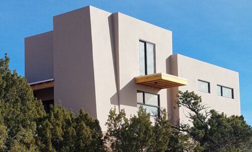 A modern Santa Fe-inspired house sitting on top of a hill, built by a skilled home builder and contractor.