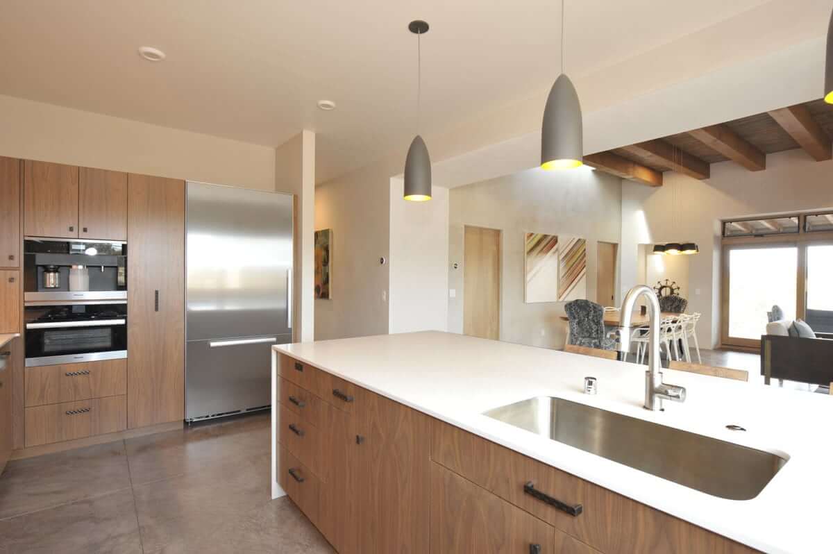 A Santa Fe-inspired kitchen with wooden cabinets and stainless steel appliances, expertly designed by a home designer.