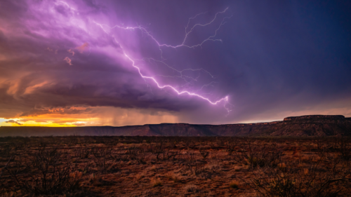 A lightning bolt illuminates a desert landscape.