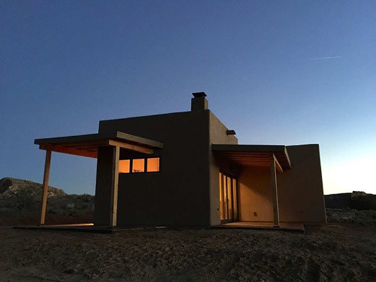 A Santa Fe style home nestled in the desert at dusk.