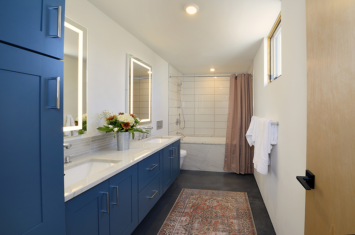 A Santa Fe bathroom with blue cabinets and a rug.