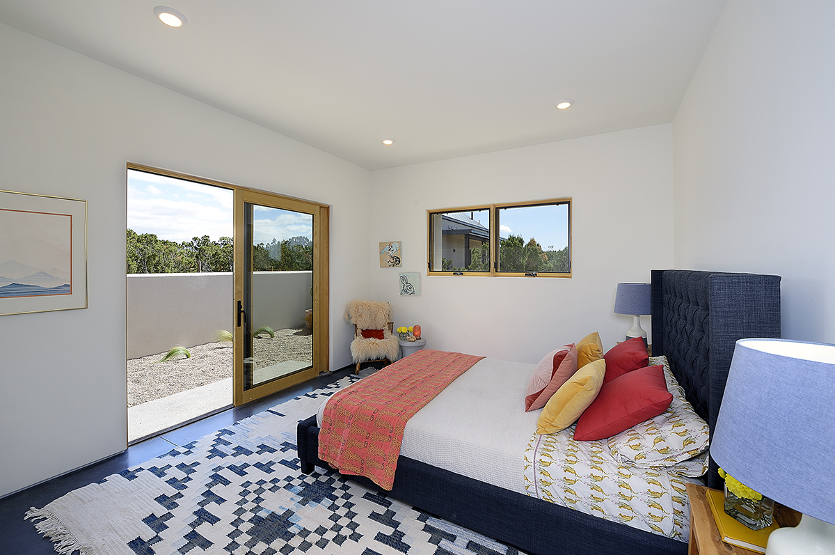 A bed in a room with a sliding glass door designed by a home designer.