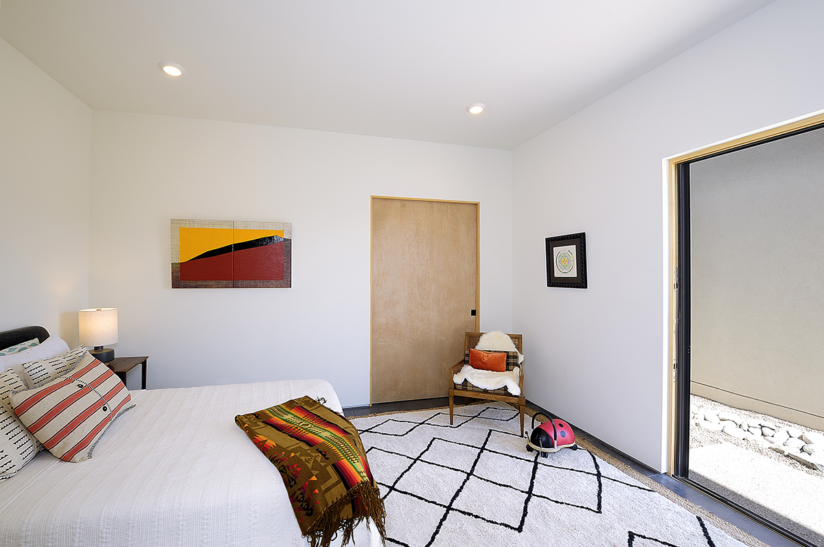 A Santa Fe inspired bedroom with a bed and a rug, designed by an architect.