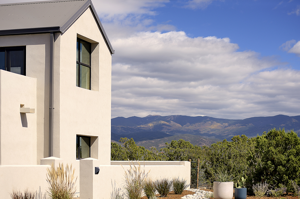 A home designer in Santa Fe created a beautiful white house, perfectly situated with mountains in the background.