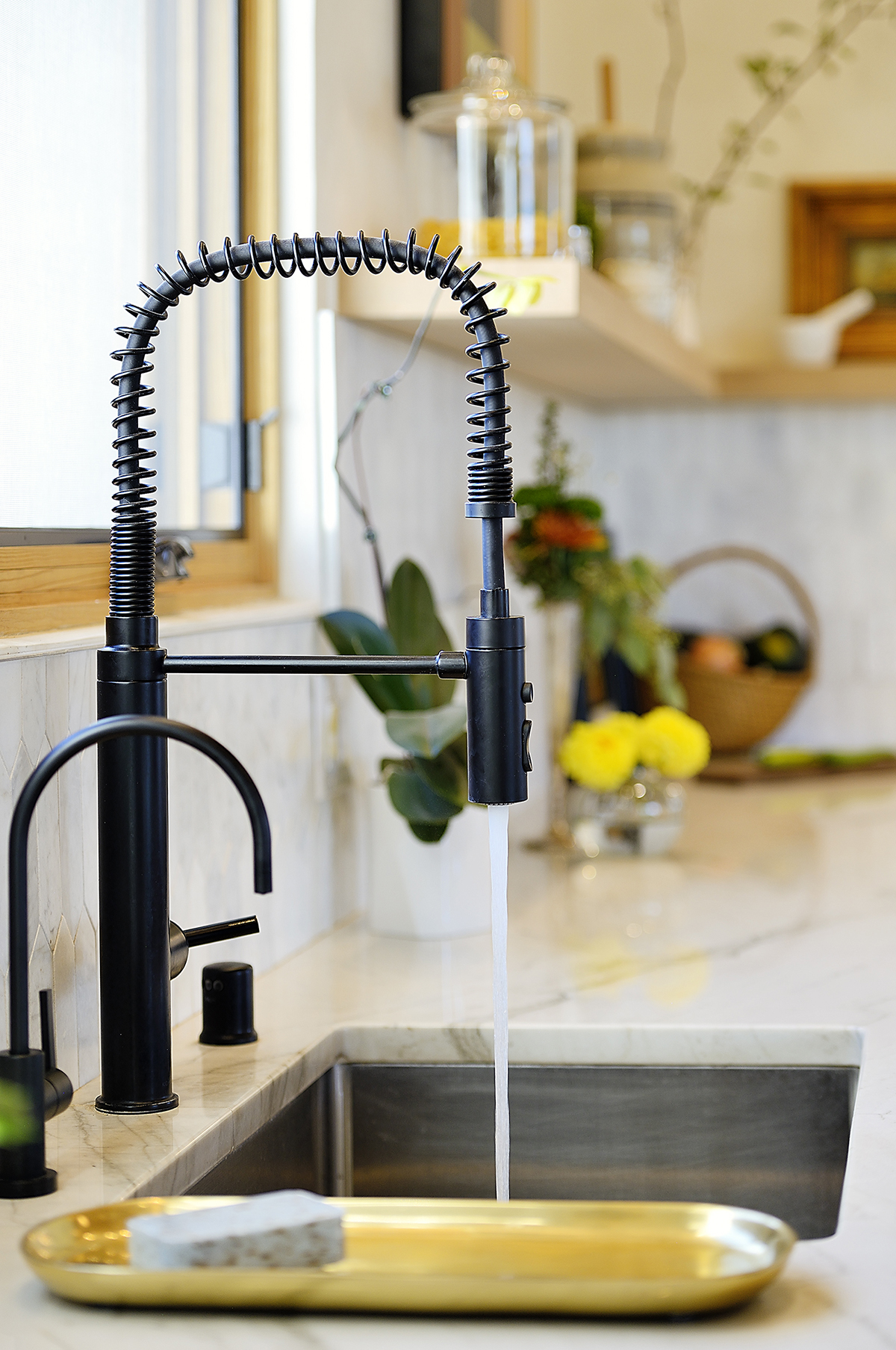 A kitchen sink with a black faucet and a gold tray designed by an architect.