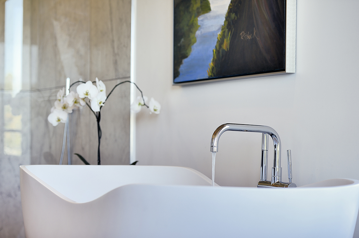 A bathroom with a bathtub and a painting on the wall, designed by a home designer or architect.