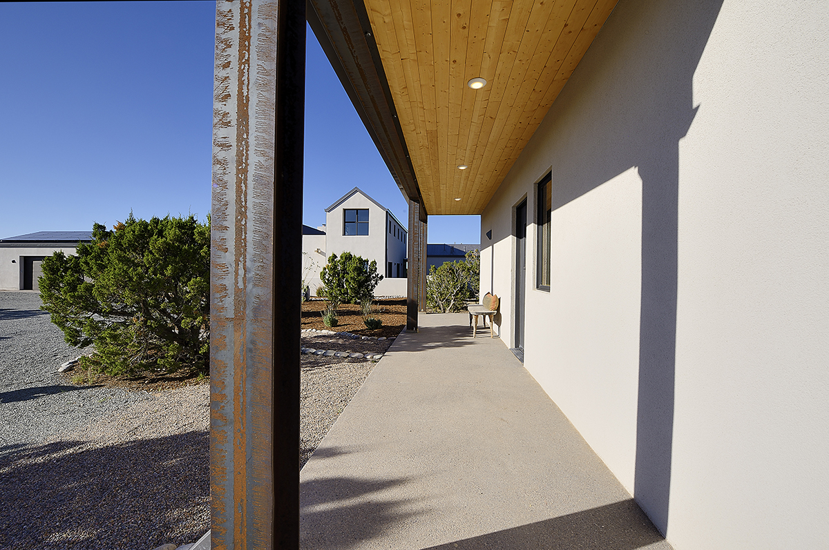 A home with a wooden porch and a metal railing, constructed by a skilled contractor.