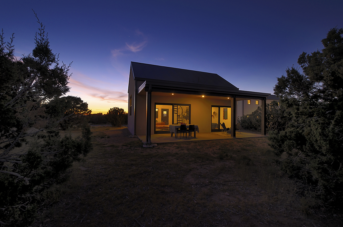 A house in the middle of a field at dusk, designed and built by a home designer.