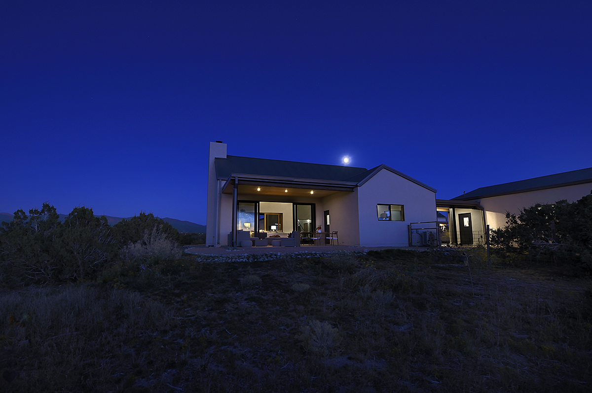 A Santa Fe-inspired house peacefully situated in the middle of a field, showcasing the exquisite craftsmanship of an architect and home builder.