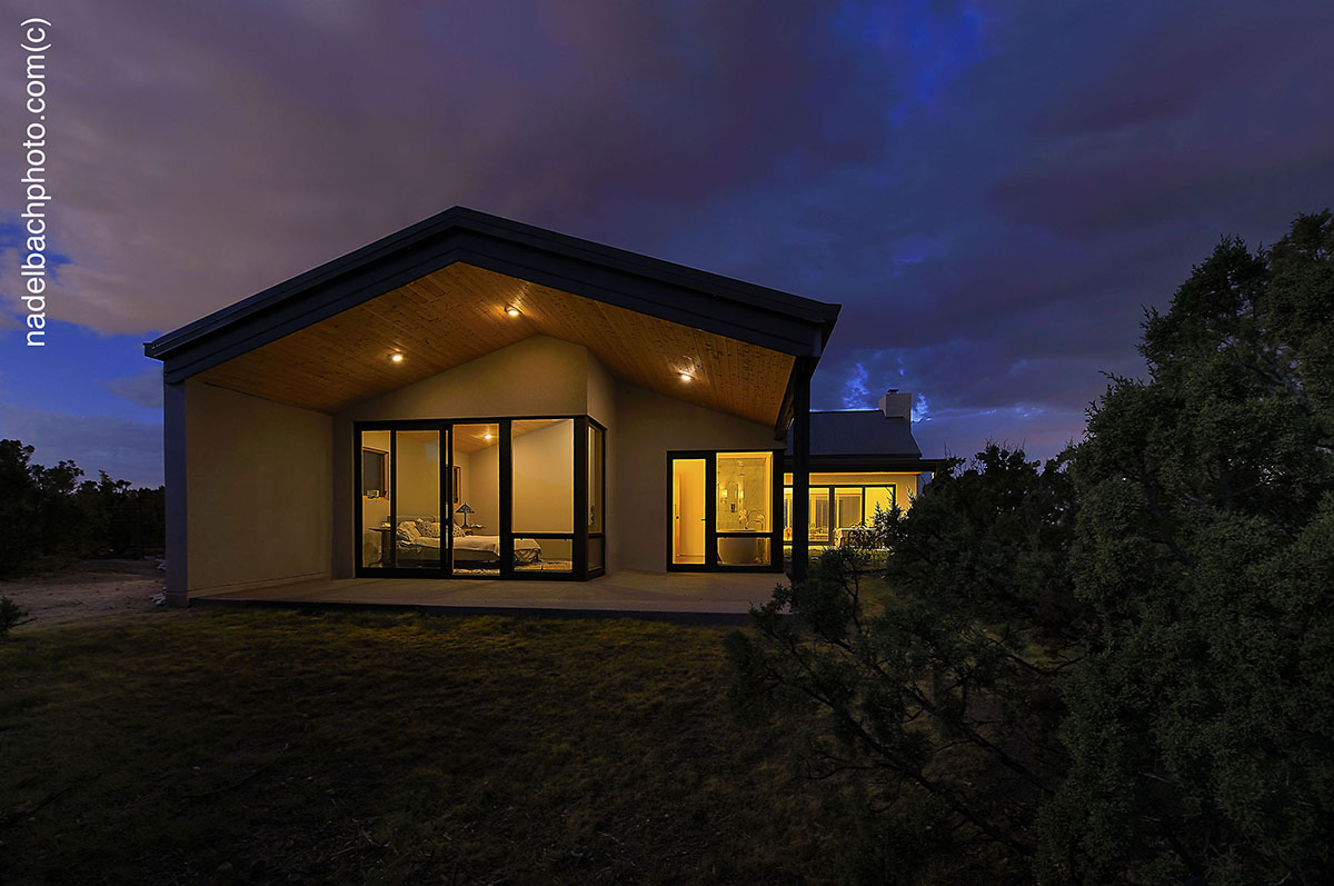 A home builder expertly constructs a house in the middle of a field at night.