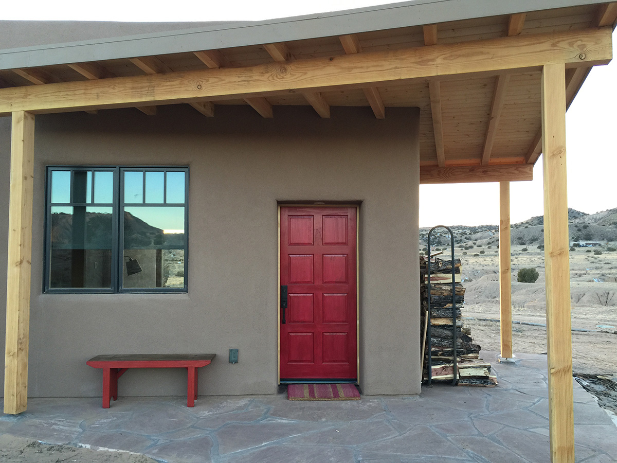 An adobe house with a red door designed by an architect