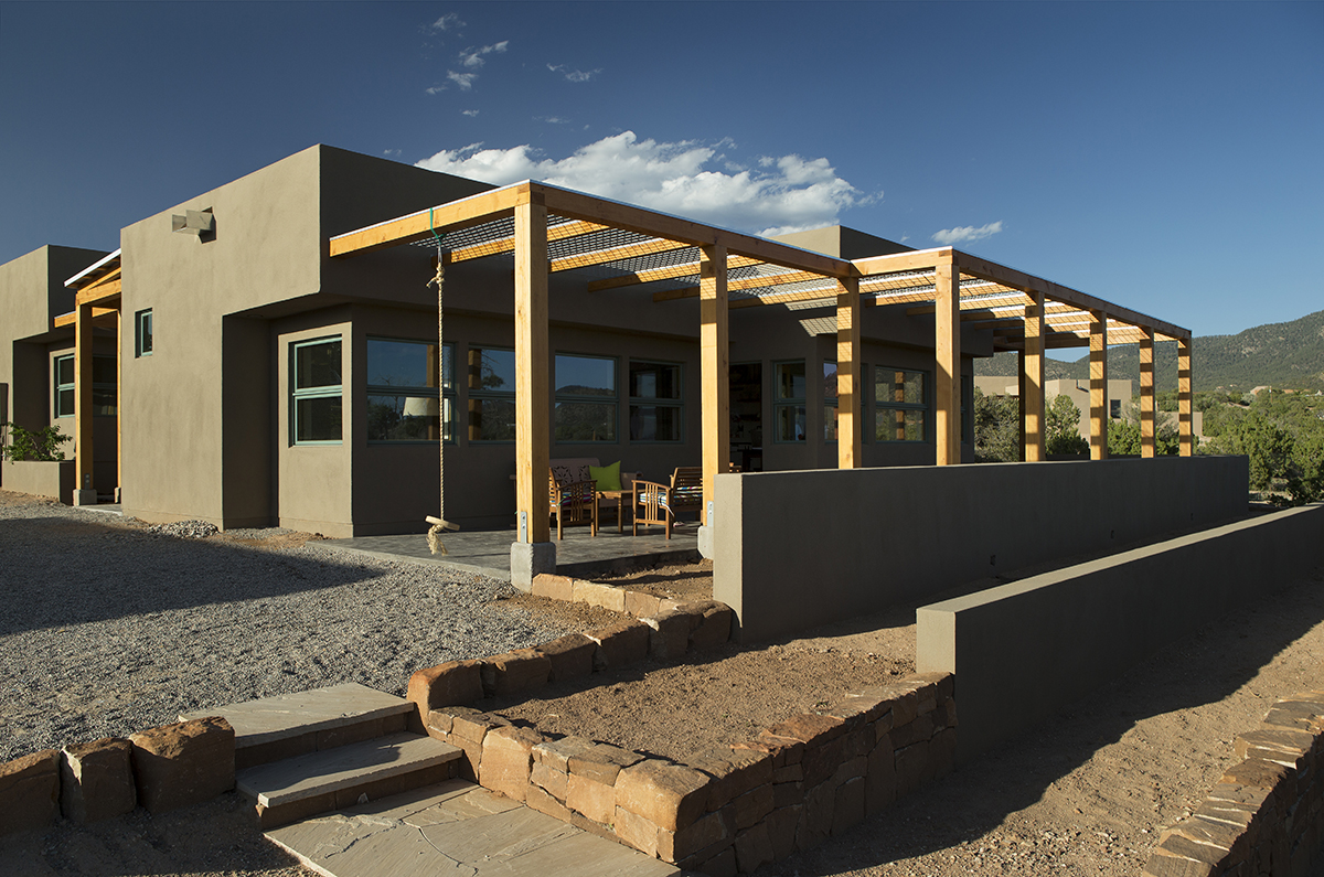An architect-designed house in the desert with a wooden walkway.