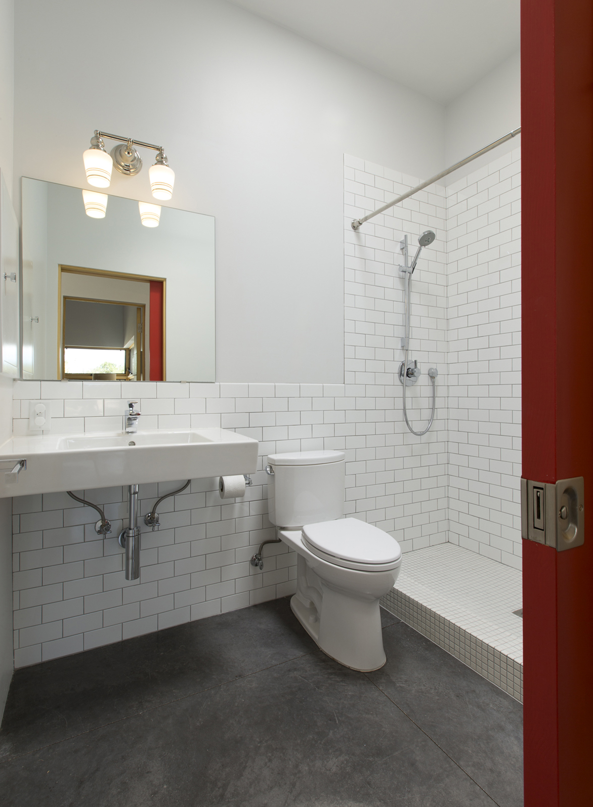 A home designer envisioned a white tiled bathroom with a red door, giving it a touch of Santa Fe charm.
