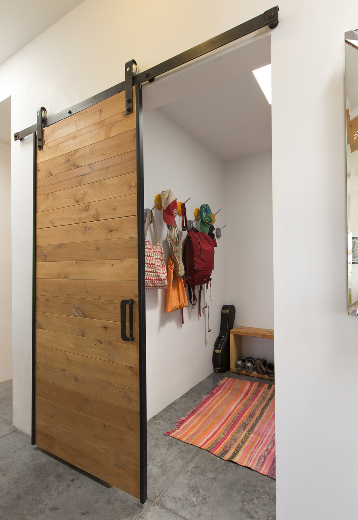 A sliding barn door in a room with a rug created by a home designer.