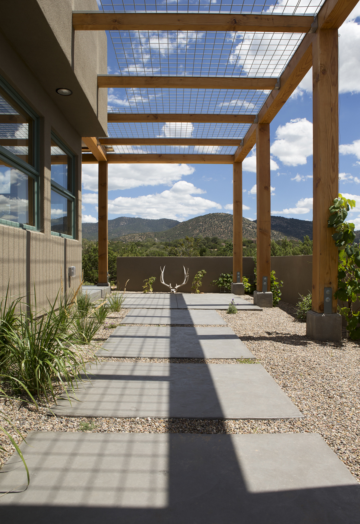 A concrete patio with a wooden pergola designed by a Santa Fe architect.