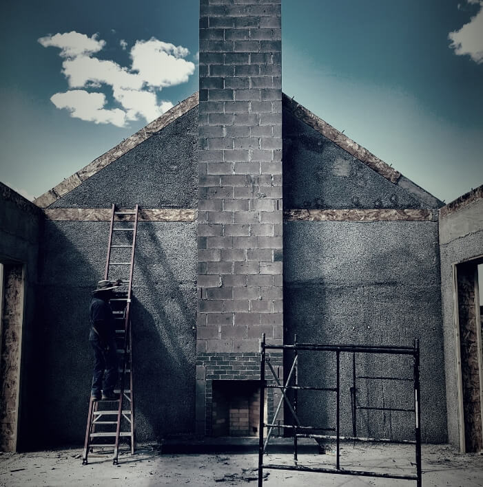 An architect is standing on a ladder in front of a house.