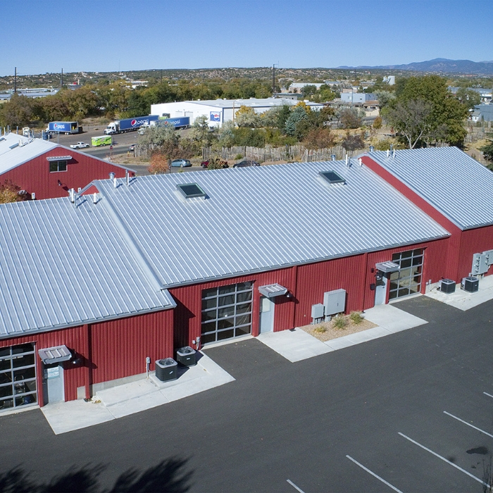 An aerial view of a red building with a metal roof, designed by a home designer.