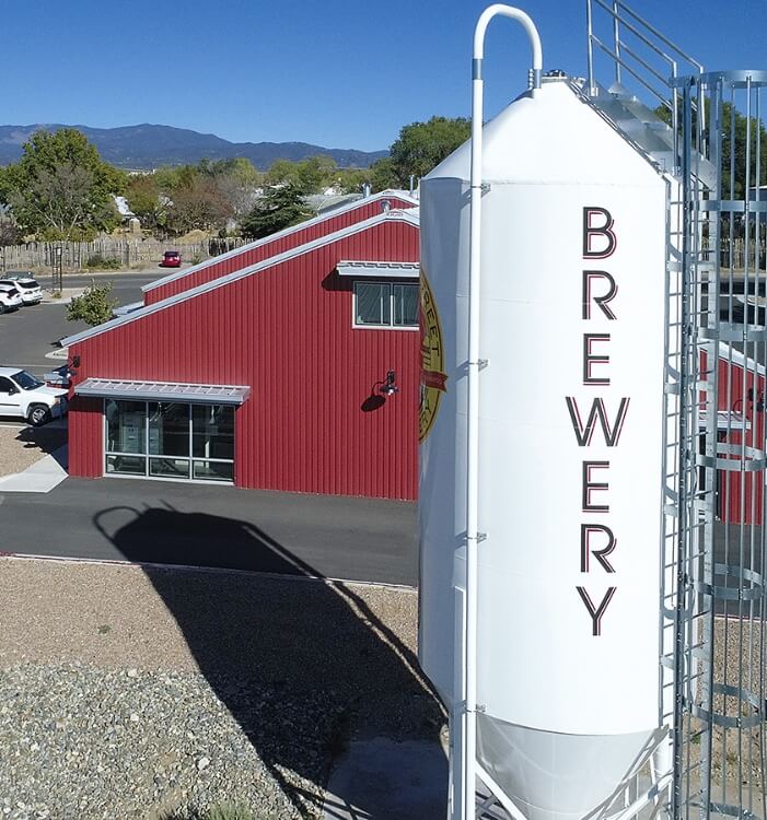         A red building with a sign that says brewery designed by an architect.