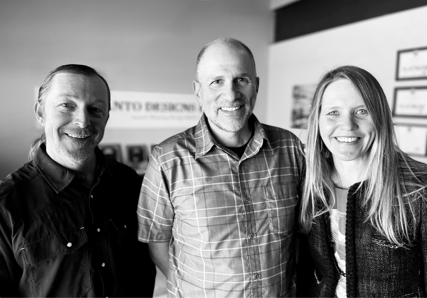 Three people smiling in front of a black and white photo in Santa Fe.