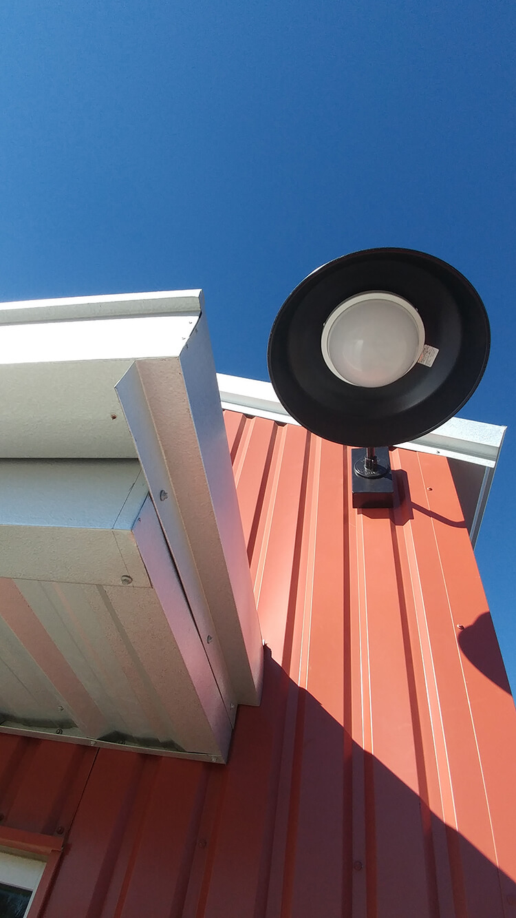 A solar light is mounted on the side of a building designed by a home designer.