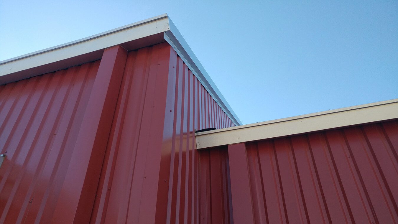 The top of a red metal building with a blue sky, perfect for a Santa Fe architect or contractor project.