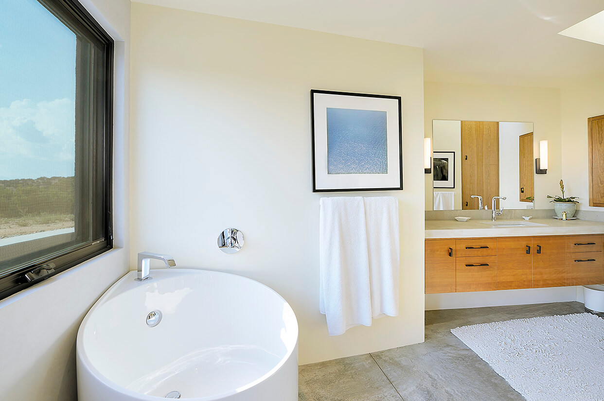 A Santa Fe-style bathroom with a large window and a white tub.