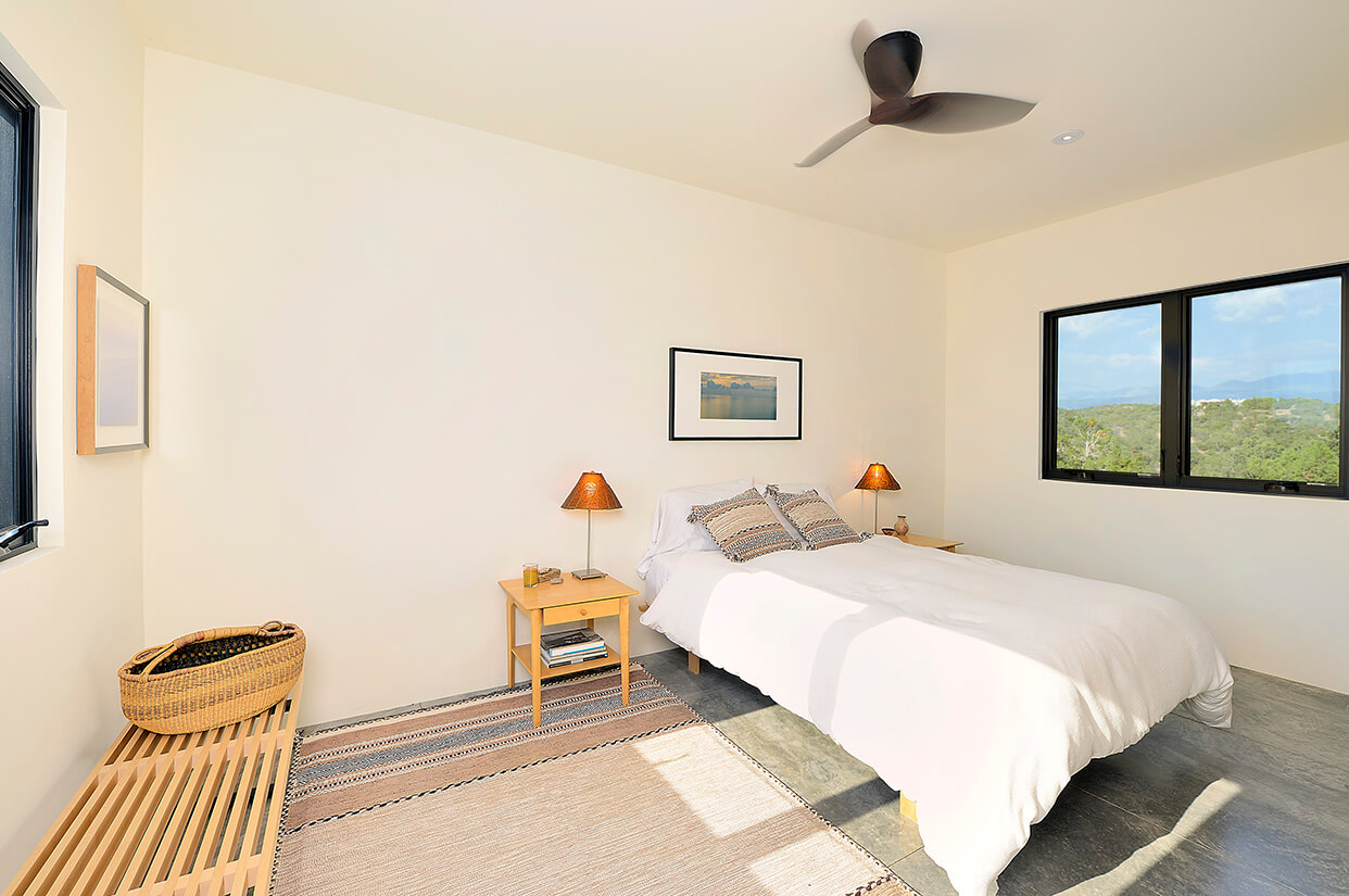 A bedroom designed by an architect with a comfortable bed and a fan, created by the home builder or contractor.