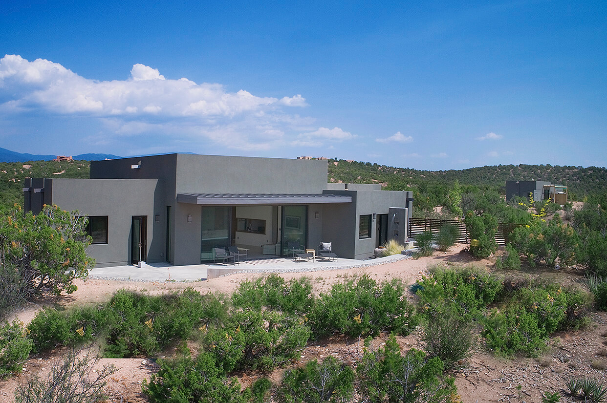 A modern home designed and built by a home designer and contractor sits in the middle of the desert.