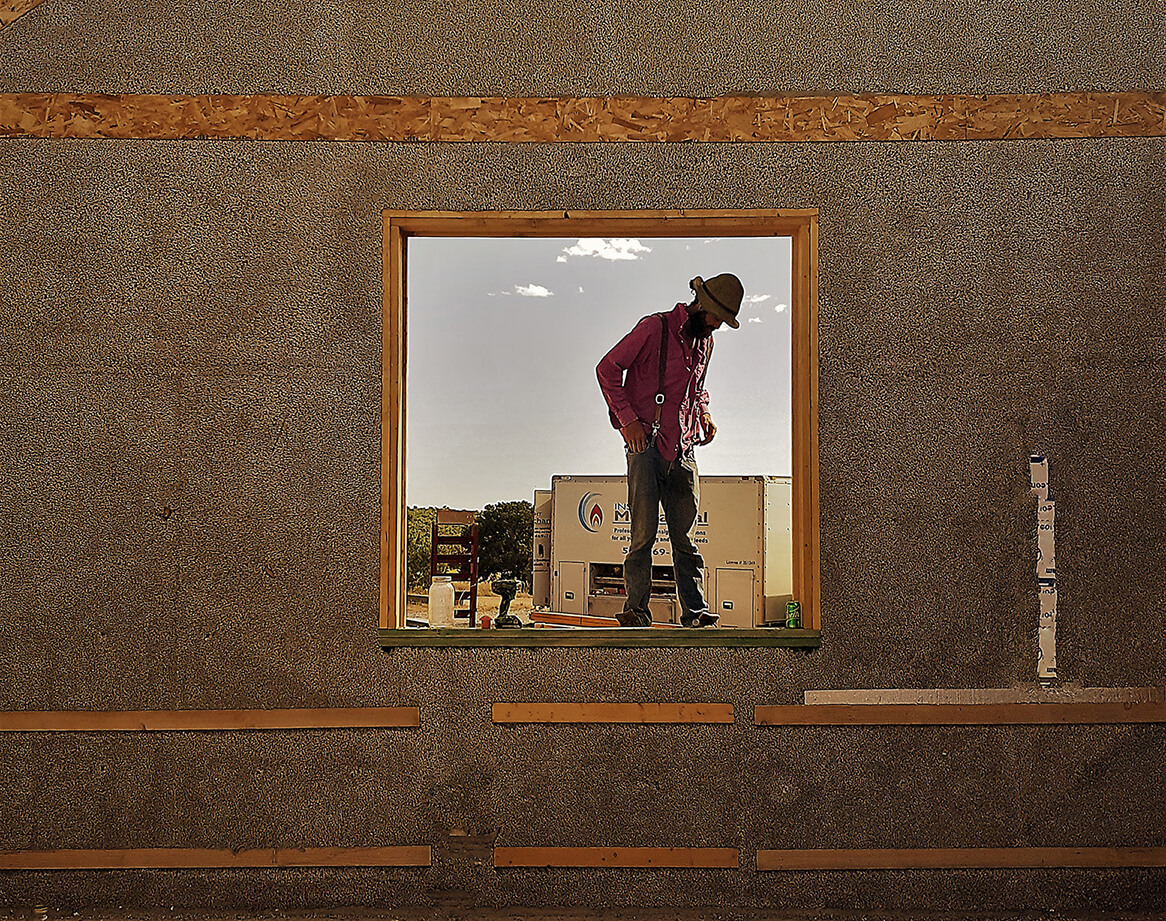 A Santa Fe architect standing on a ladder in front of a window.