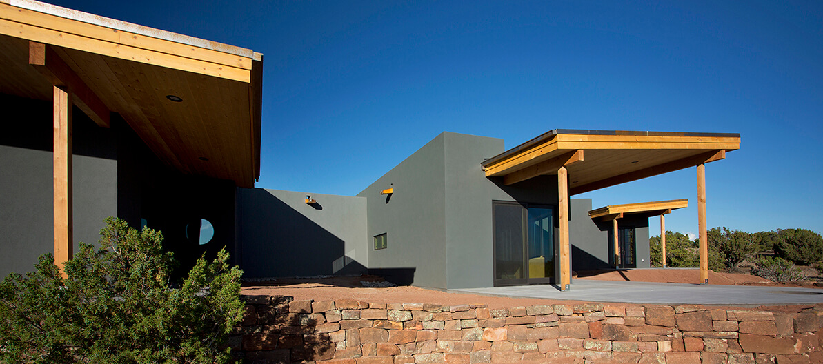 A modern Santa Fe style house in the desert with a wooden roof, designed by a home designer and built by a contractor.