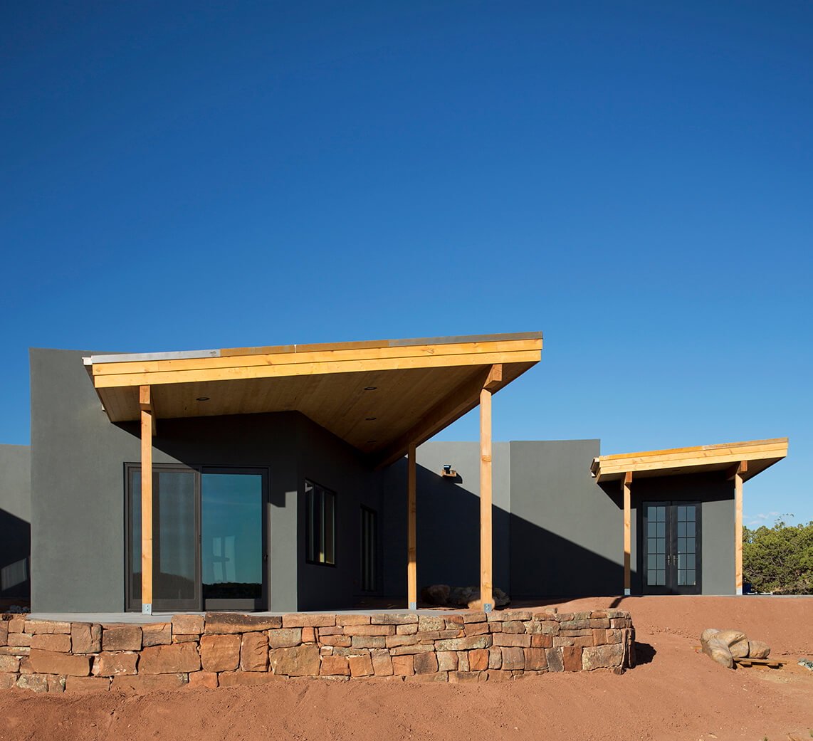 A Santa Fe-inspired house in the desert with a wooden roof, designed by an architect and home designer.