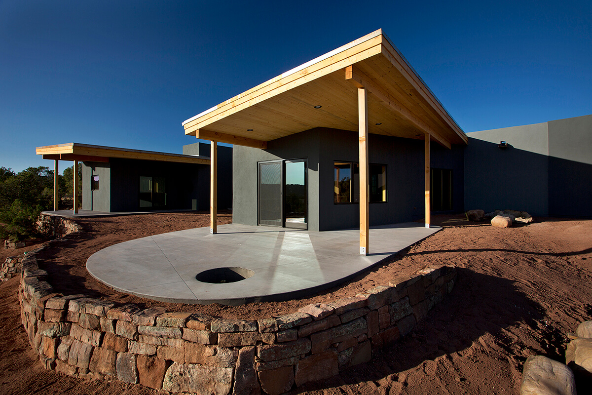 A Santa Fe-style home in the desert with a wooden deck, designed by an architect.
