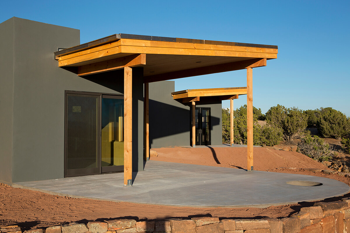A Santa Fe-style house in the desert with a wooden deck, designed by an architect.