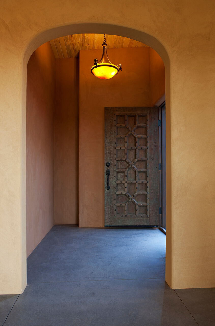         A Santa Fe-inspired hallway adorned with a stylish light fixture elevates the ambiance of this beautifully designed home.