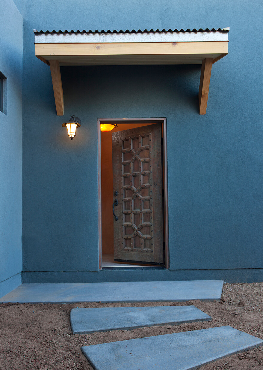 A blue house with a wooden door, designed by a home designer.