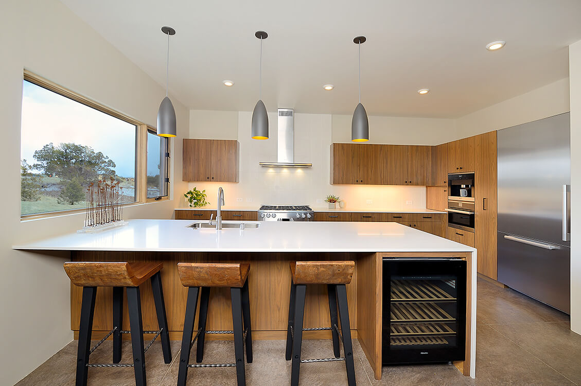 A kitchen designed by a home designer in Santa Fe, featuring a refrigerator and stools.
