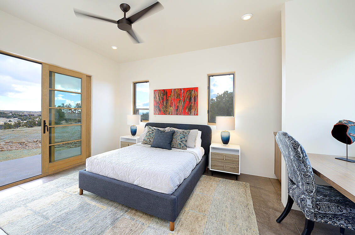 A sliding glass door enhances the bedroom with a comfortable bed, perfectly designed by a skilled home builder.