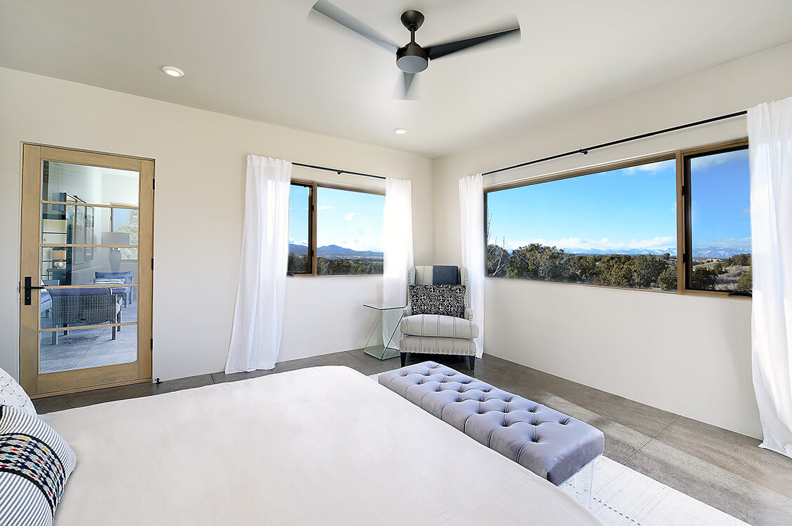 A bedroom designed by a home designer with a ceiling fan and a view of the mountains.