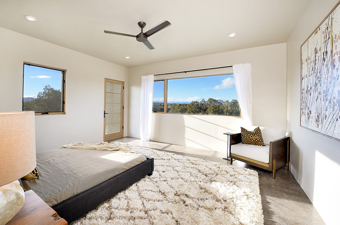 A bedroom designed by a home designer with a bed and a ceiling fan.