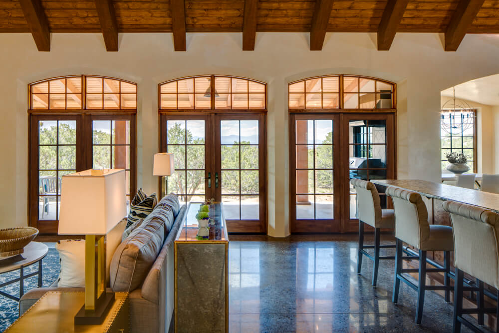A Santa Fe style living room with a fireplace and large windows, created by a skilled home builder and contractor.