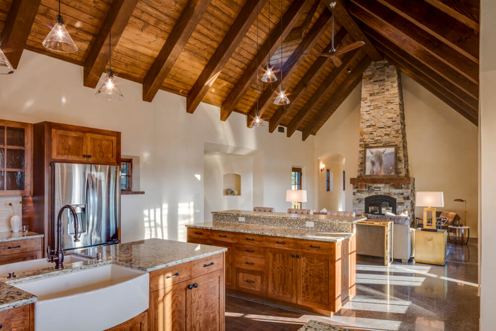 A Santa Fe-inspired kitchen with wood beams and a stone fireplace, expertly crafted by a skilled contractor and home builder.