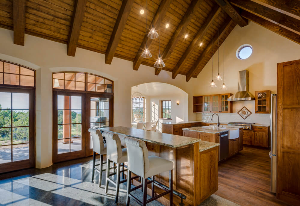 A large kitchen with wood beams and a large island designed by a Santa Fe home designer.