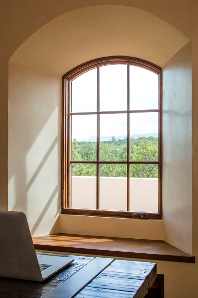 An architect's laptop positioned on a table with a serene view of Santa Fe through the window.