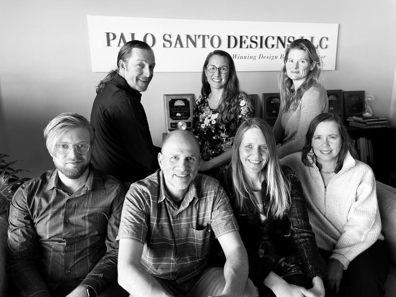 A group of people posing in front of a sign that says Palo Santo Designs, featuring home designers from Santa Fe.