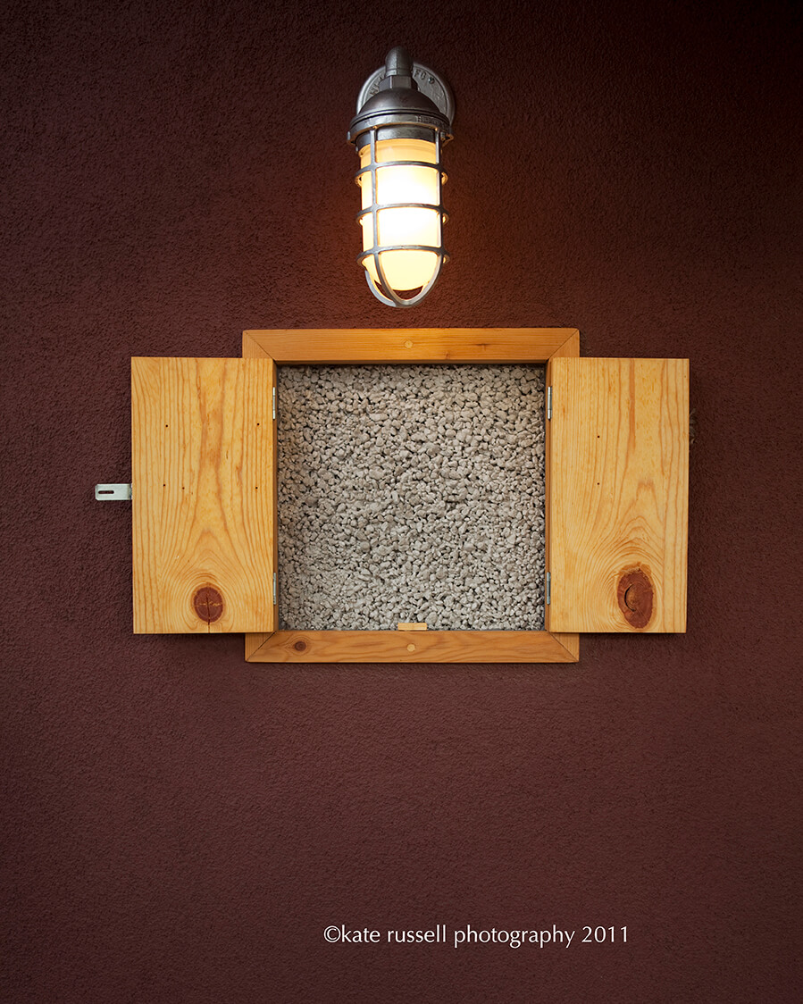 A Santa Fe-inspired wooden box on a wall with a light on it.