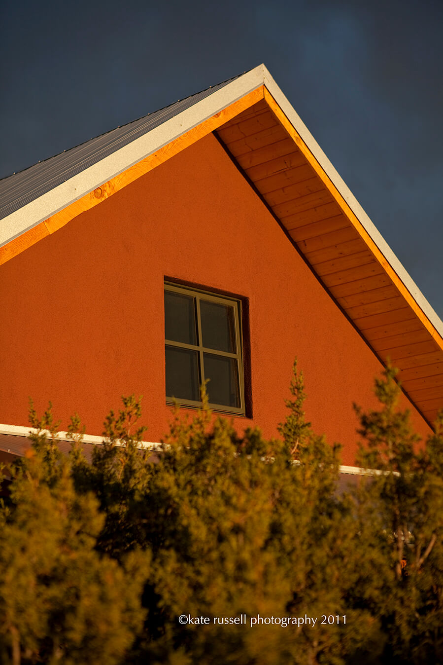 A Santa Fe contractor building a red house with a window at sunset.
