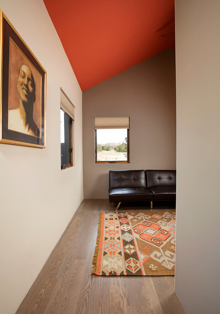 An architecturally designed living room with an orange ceiling and a stylish rug.